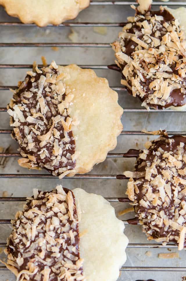 chocolate covered cookies cooling on a rack with coconut flakes and sprinkles