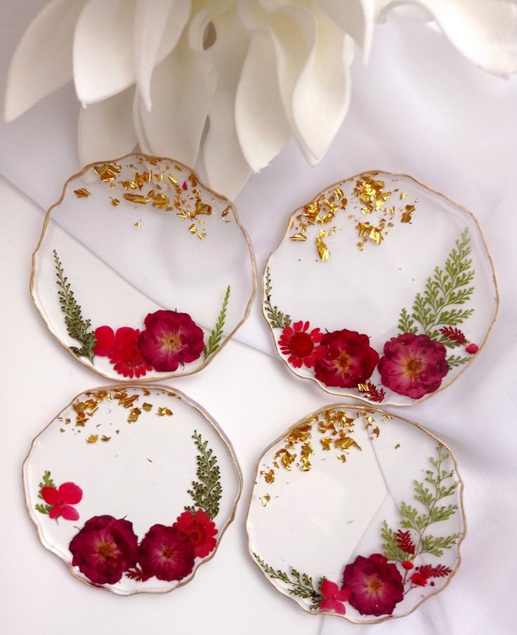 four white plates with red flowers on them