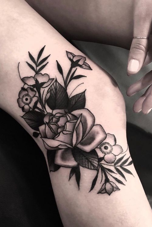 a black and white photo of a woman's leg with flowers on it,