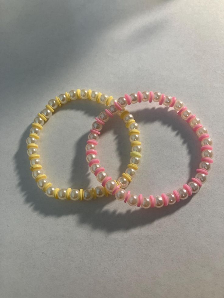 two bracelets are sitting on top of each other, one is yellow and the other is pink