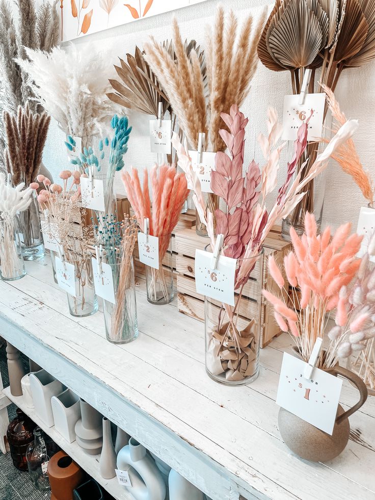 several vases filled with dried flowers on top of a table