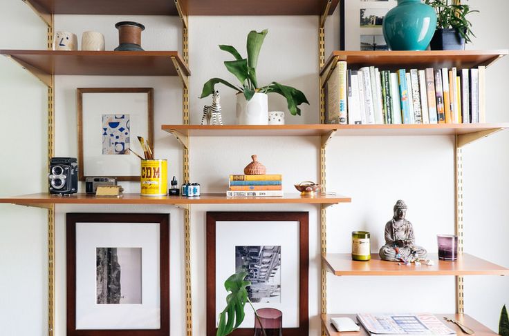 a living room with bookshelves and pictures on the wall above it, along with plants