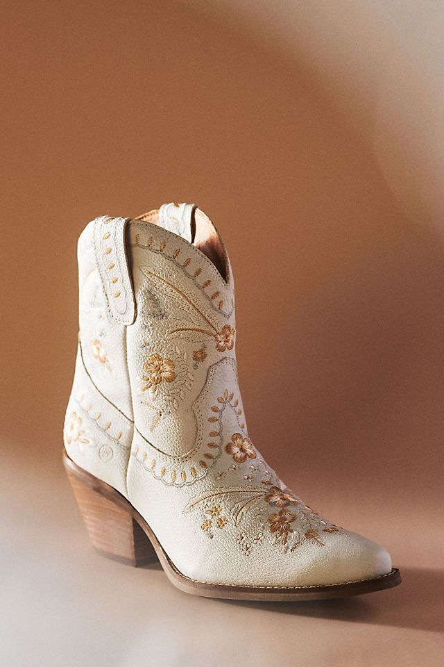 a pair of white cowboy boots sitting on top of a table