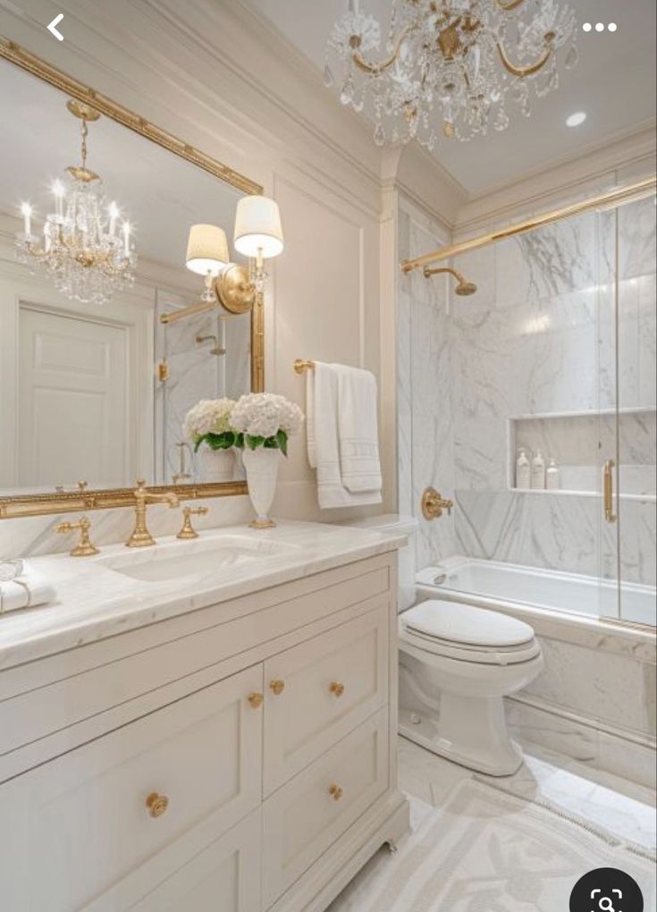 a white bathroom with gold accents and chandelier