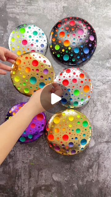 someone is painting some colorful circles on the ground with paintbrushes and paper machs