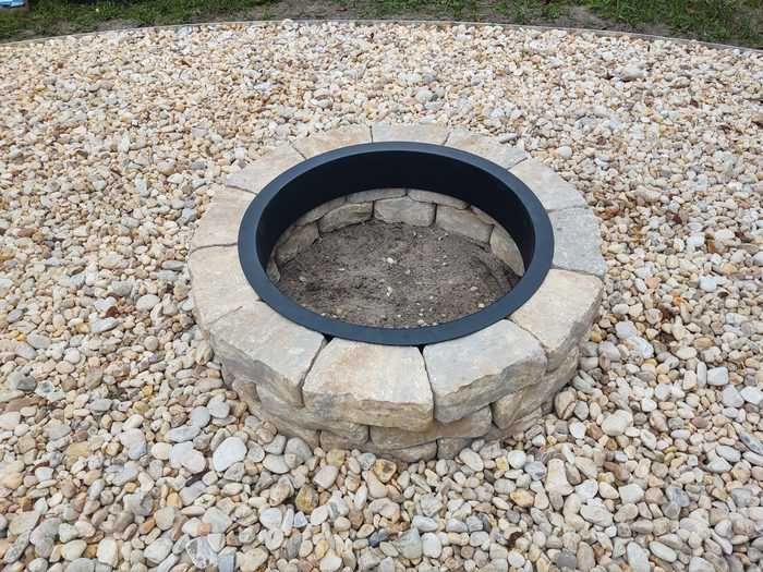 an outdoor fire pit surrounded by rocks and gravel