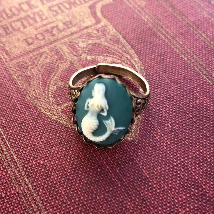 18x13mm turquoise and white acrylic mermaid cameo. On an antiqued brass cigar band style ring. Easy to adjust to most sizes. Available in both antiqued silver and antiqued brass. I also have a matching necklace in my shop (see in last photo). Pirate Ring, Pirate Jewelry, Mermaid Ring, Steampunk Accessories, Cameo Jewelry, Cameo Ring, Vintage Style Jewellery, Cameo Necklace, Steampunk Jewelry