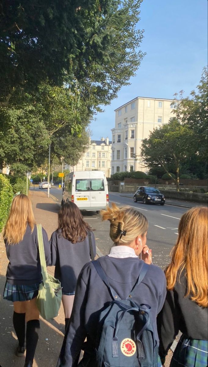 three girls walking down the street with their backpacks on