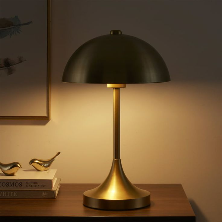 a lamp that is on top of a table next to some books and a bird figurine