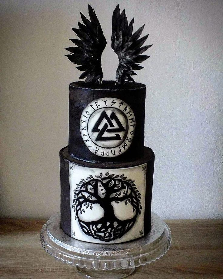 a three tiered cake with black and white designs on the side, topped with an eagle