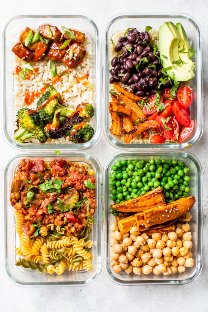 four plastic containers filled with different types of vegetables and pasta salads on top of each other