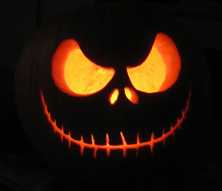 a carved pumpkin with glowing eyes in the dark