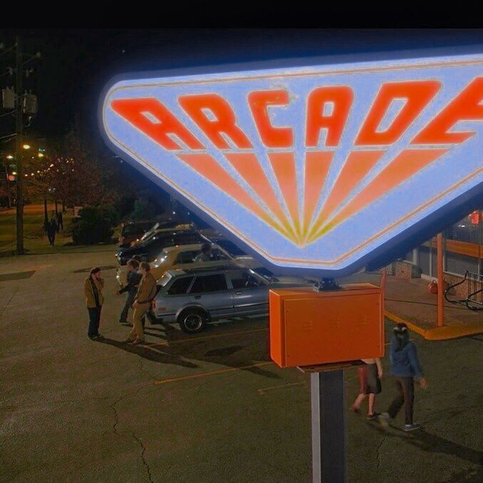 people are standing in the parking lot near an arcade sign