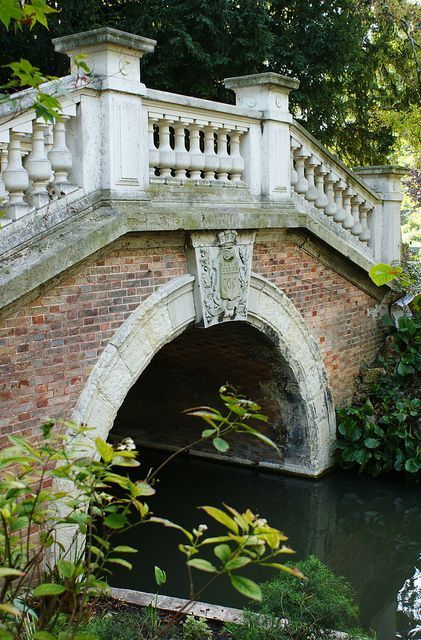 an old bridge over a small river in a park