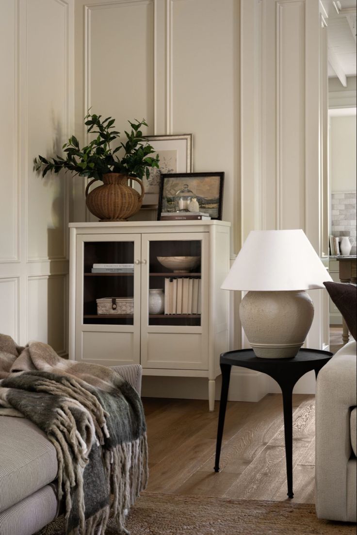 a living room filled with furniture and a lamp on top of a wooden floor next to a white wall