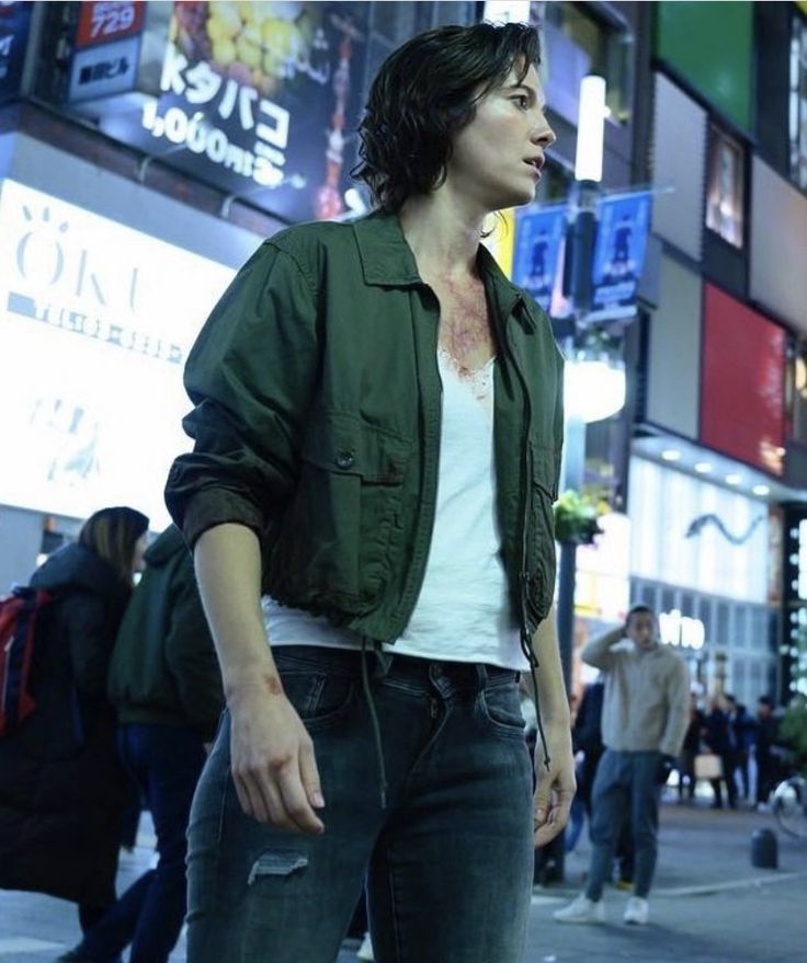 a man standing in the middle of a busy city street with his hand on his hip