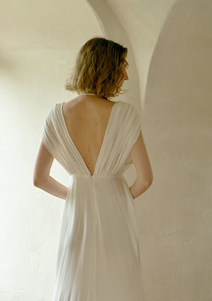 the back of a woman's white dress is seen from behind as she stands in an archway