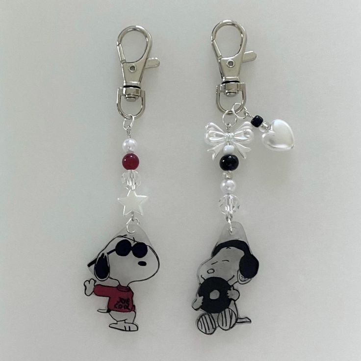 two key chains with charms attached to them on a white surface, one has a dog and the other has a bow