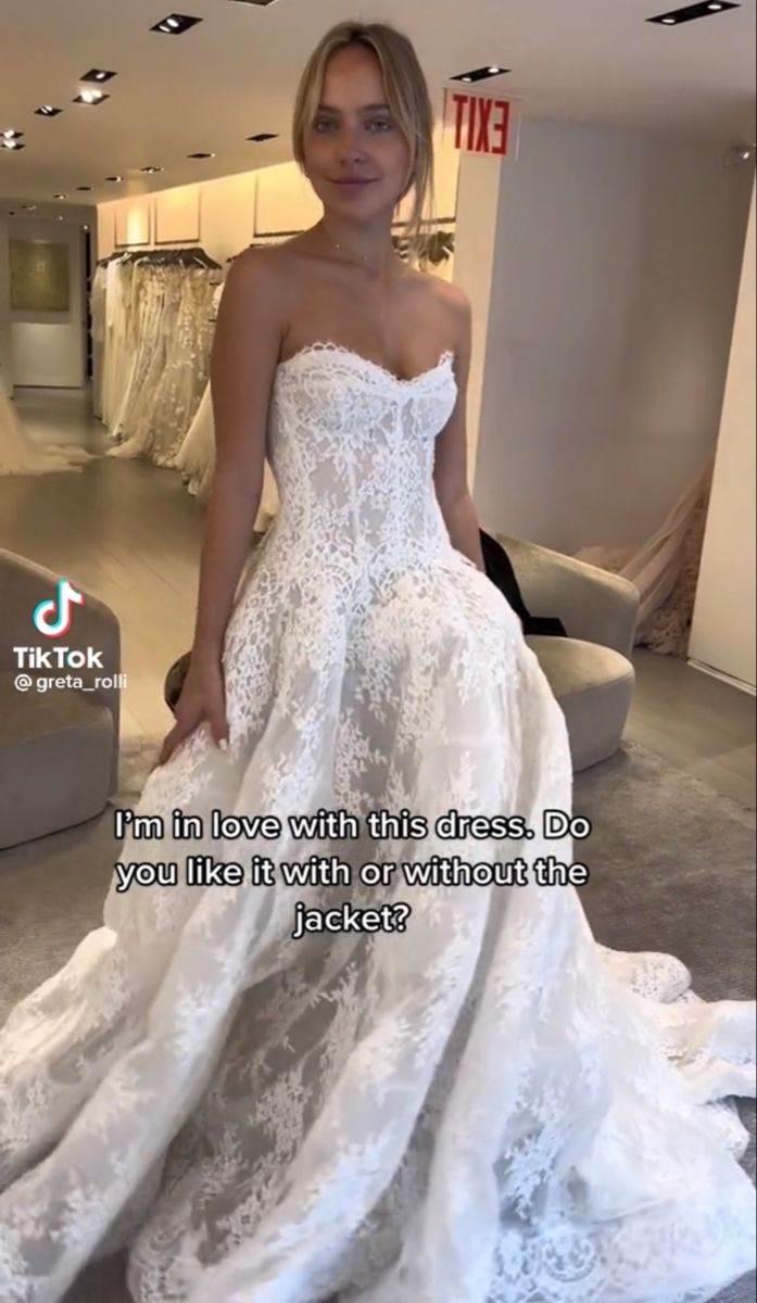 a woman in a white wedding dress standing next to a couch and looking at the camera