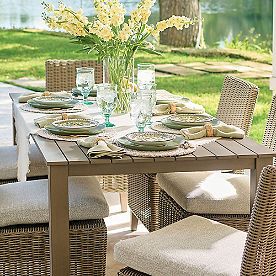 a dining table set with place settings and flowers in vase on the top, outside