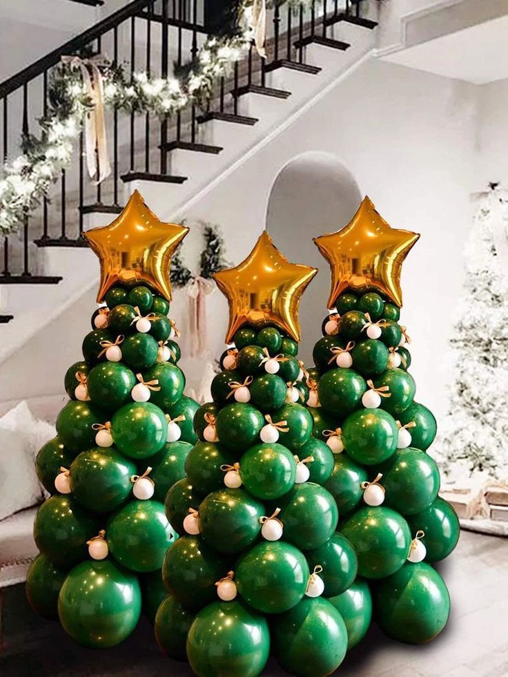 a christmas tree made out of balloons with gold stars on top and green balls in the middle