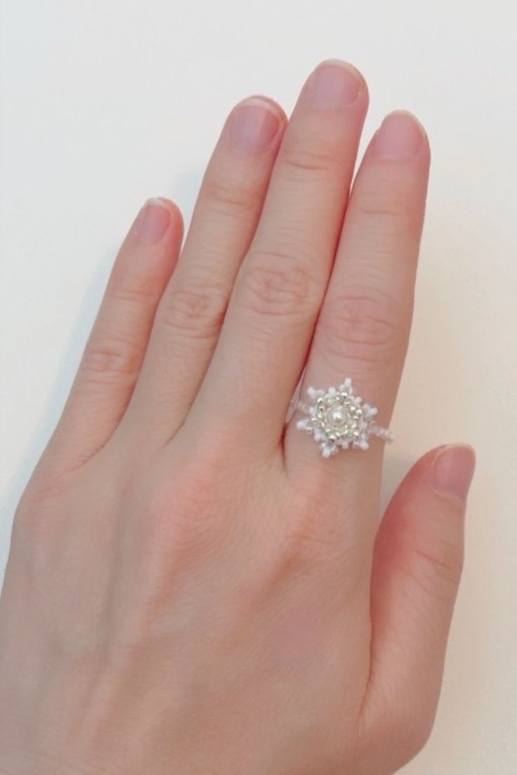 a woman's hand with a diamond ring on top of her left hand, against a white background