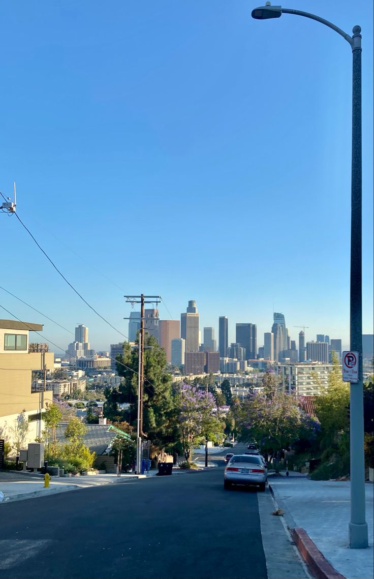 a car is driving down the street in front of a cityscape with tall buildings