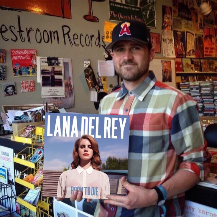 a man holding up a book in front of a room full of books and magazines