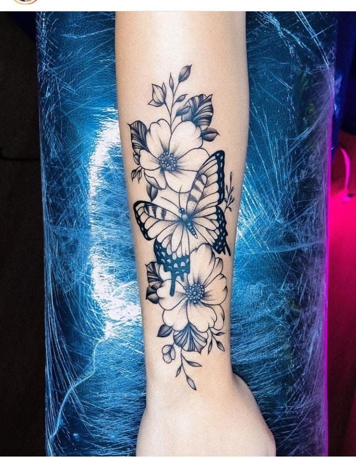 a butterfly and flowers tattoo on the left arm, with blue background in the foreground