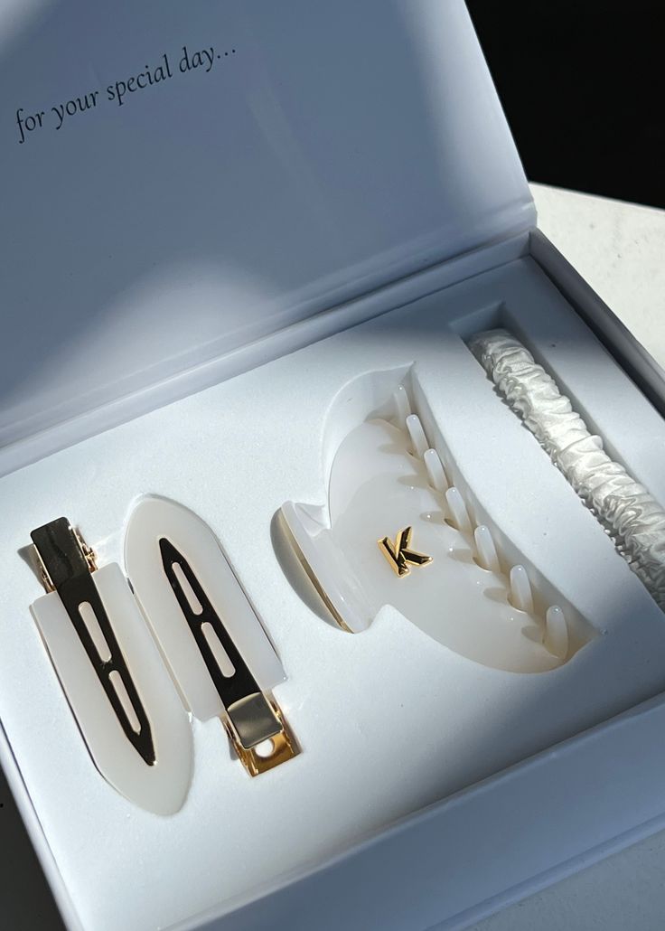 two pairs of white and gold jewelry sitting in a box on top of a table