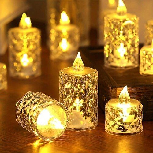 several lit candles sitting on top of a wooden table next to each other with lights in them