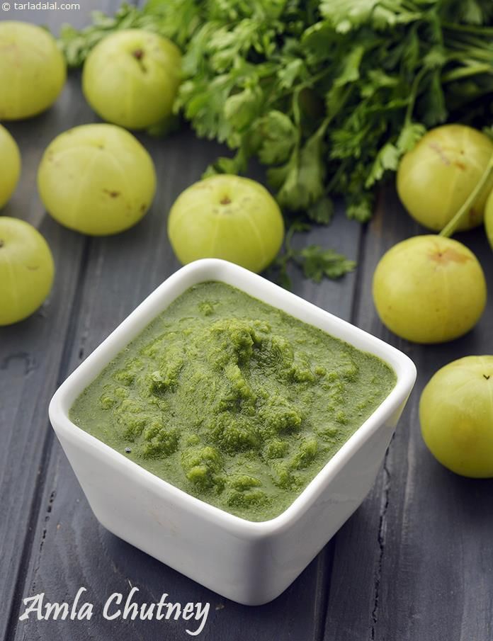 a white bowl filled with green pesto next to apples and parsley on a wooden table