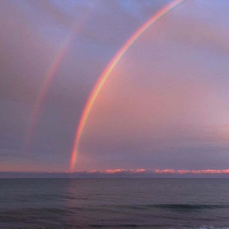 two rainbows in the sky over an ocean