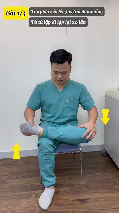 a man in scrubs sitting on a chair and holding his leg with both hands