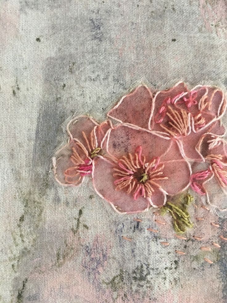 three pink flowers are sitting on a piece of fabric