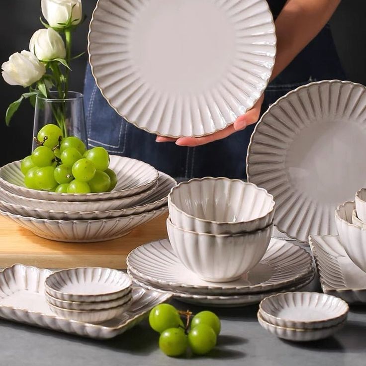 a table topped with plates and bowls filled with green apples next to white tulips