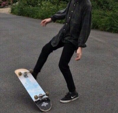 a young man riding a skateboard on top of a paved road next to bushes