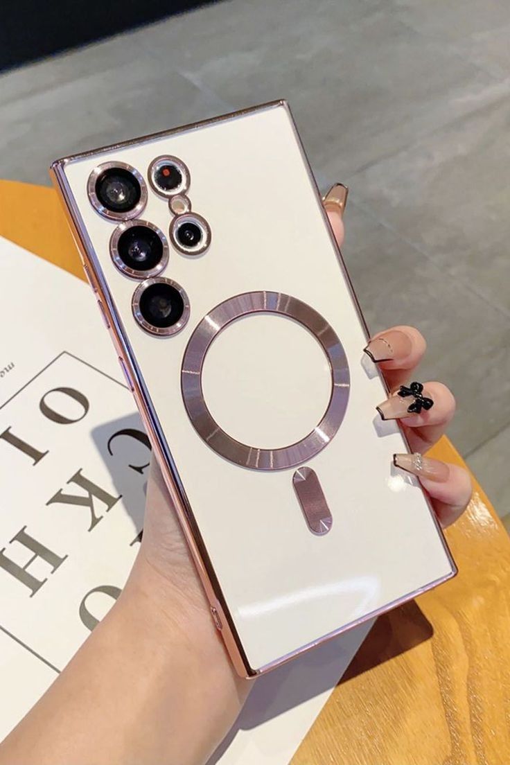 a woman's hand holding a white and silver cell phone with three cameras on it