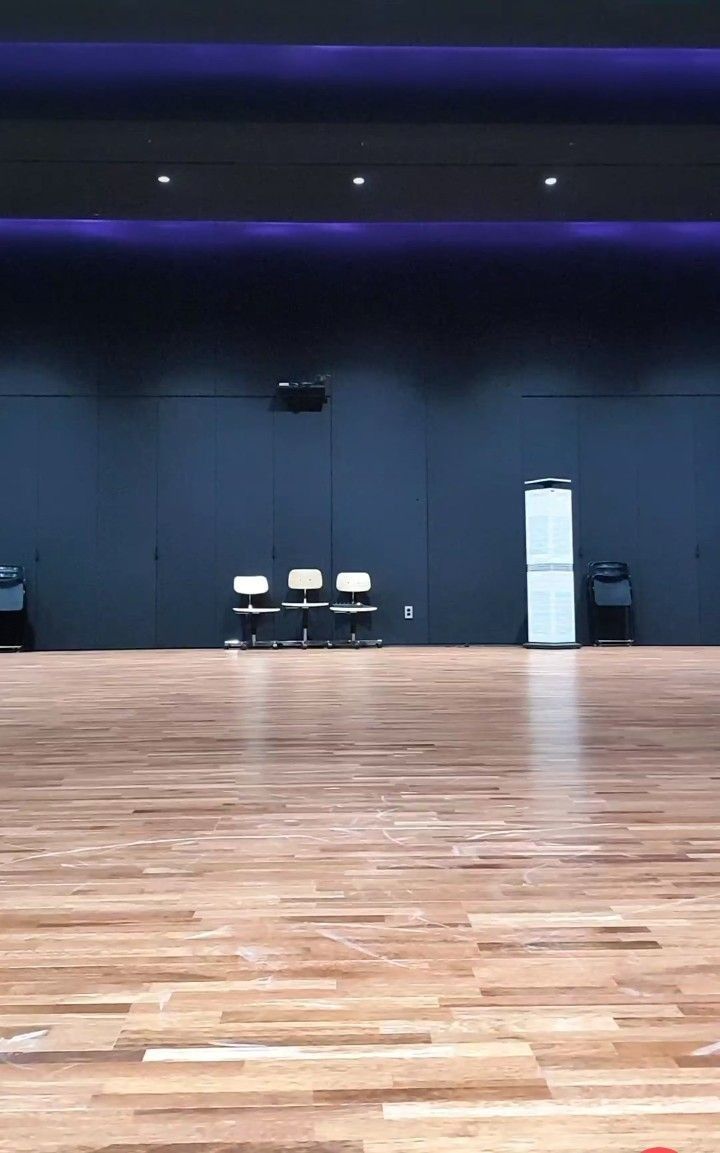 an empty dance studio with hard wood floors and purple lighting on the wall behind it