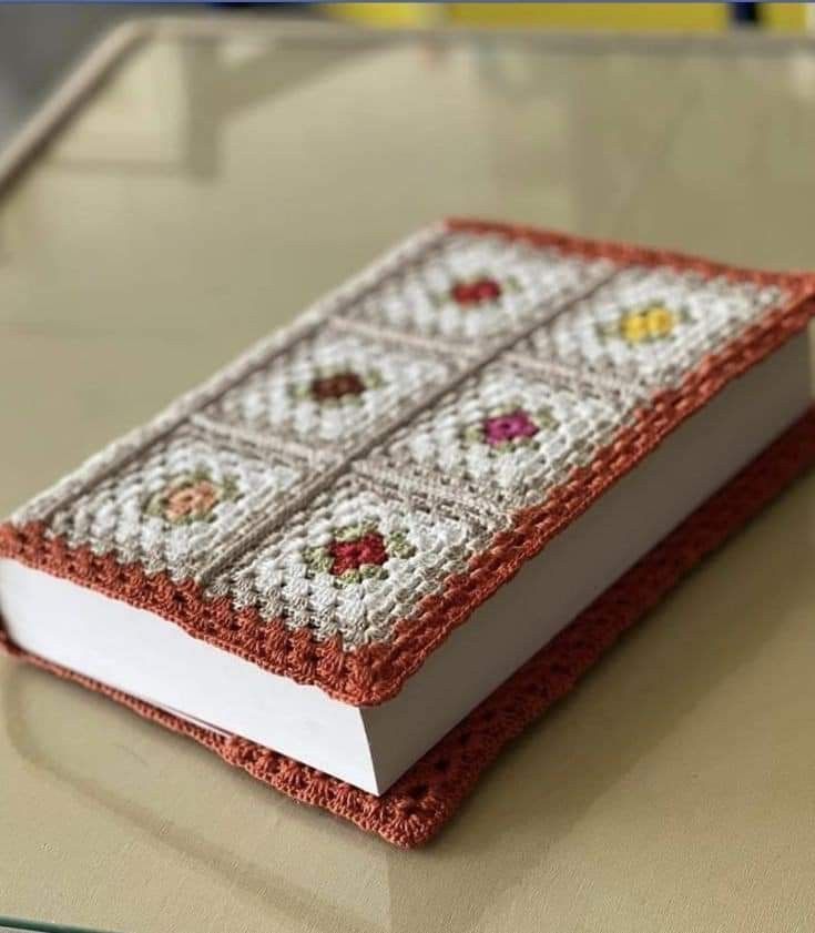 an open book on top of a table covered in cross - stitchs and beads