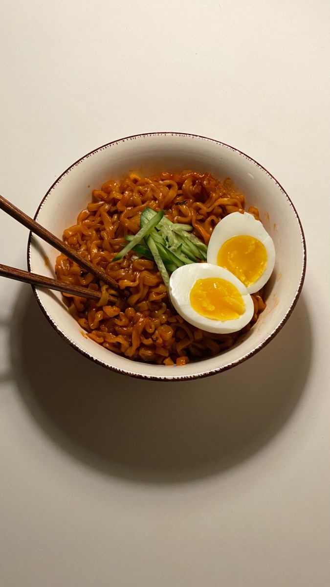 a bowl filled with noodles and hard boiled eggs on top of it next to chopsticks