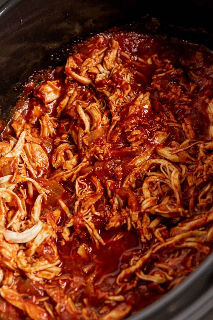 shredded meat in a crock pot with sauce and onions on the side, ready to be cooked