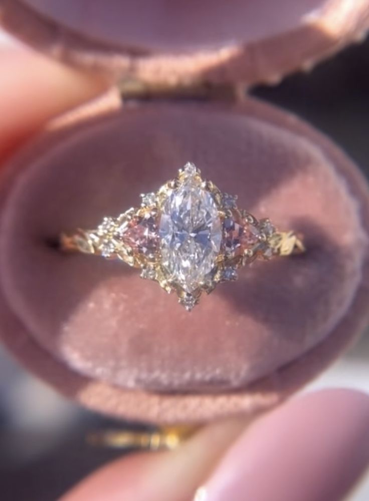 a close up of a person's hand holding an engagement ring