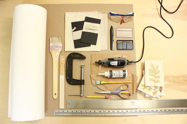 the contents of a crafting kit laid out on top of a wooden table next to a roll of paper