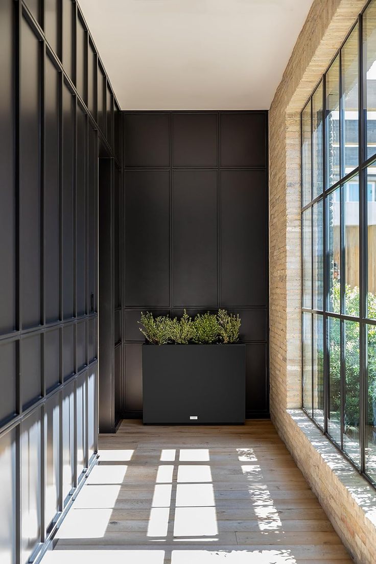 an empty hallway with large windows and plants in the planter on the side wall