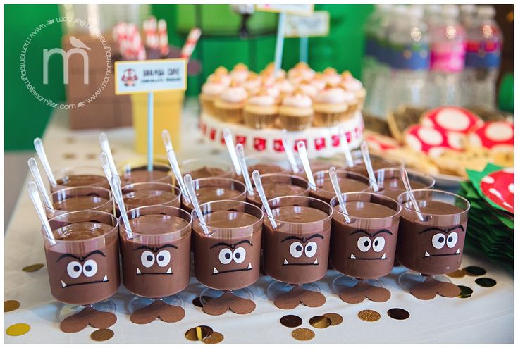 chocolate cups with googly eyes and straws are on a table in front of cupcakes