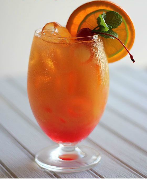 an orange drink is garnished with mint and served in a glass on a wooden table