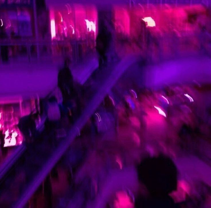 blurry image of people riding an escalator in a shopping mall at night