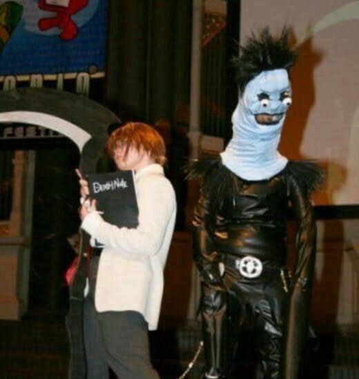 two people in costumes standing next to each other on a stage with one person dressed as a monster