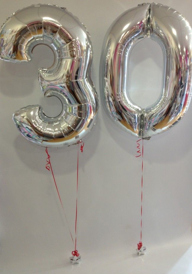 two large silver balloons with the number thirty five attached to them are hanging on a wall